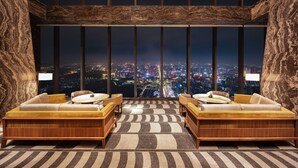 A high-rise room with two wooden sofas facing a cityscape view through large windows. - Shangri-La Nanning (Nanning)