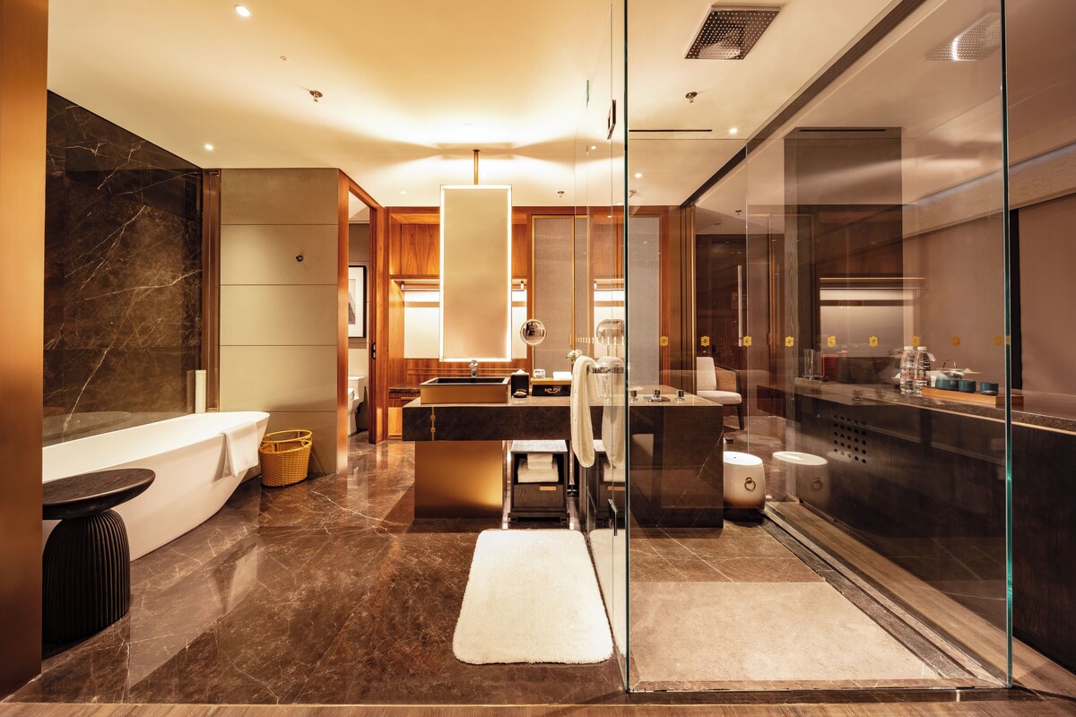 A modern bathroom with a glass-enclosed shower, a large mirror, and a vanity with a sink and countertop.
