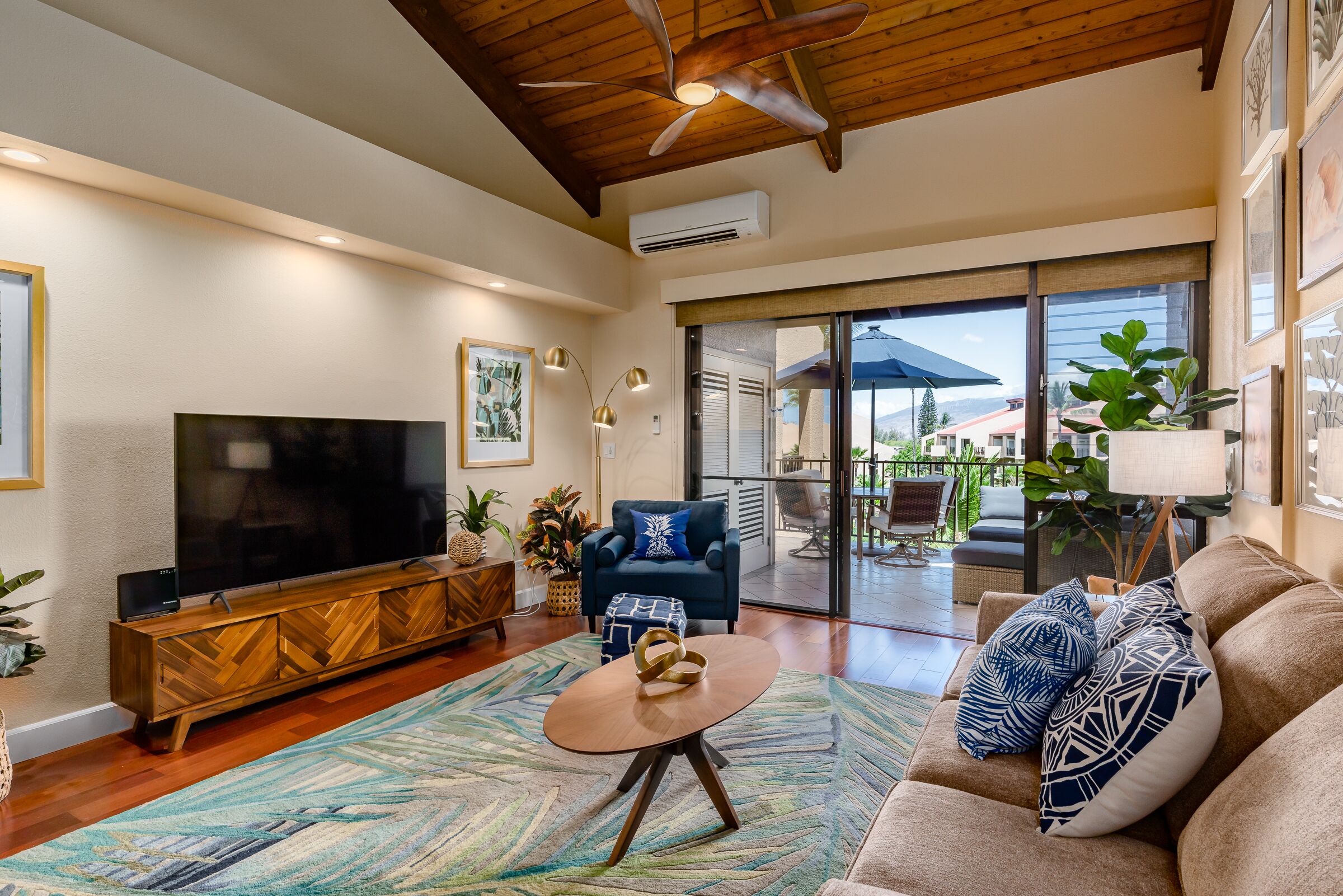 A spacious living room with a large flat-screen TV, a wooden entertainment unit, a round coffee table, and a comfortable sofa.