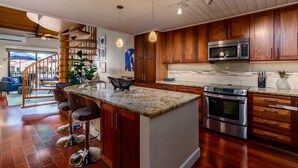Una cucina moderna con mobili in legno, elettrodomestici in acciaio inossidabile e un'isola centrale con sgabelli da bar.