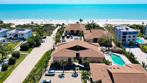 Ein Strandhotel mit mehreren Gebäuden, einem Schwimmbad und einem Strand im Hintergrund.
