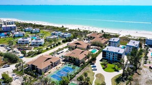 Luftaufnahme eines Küstenresorts mit mehreren Gebäuden, einem Strand und einem klaren, blauen Meer.