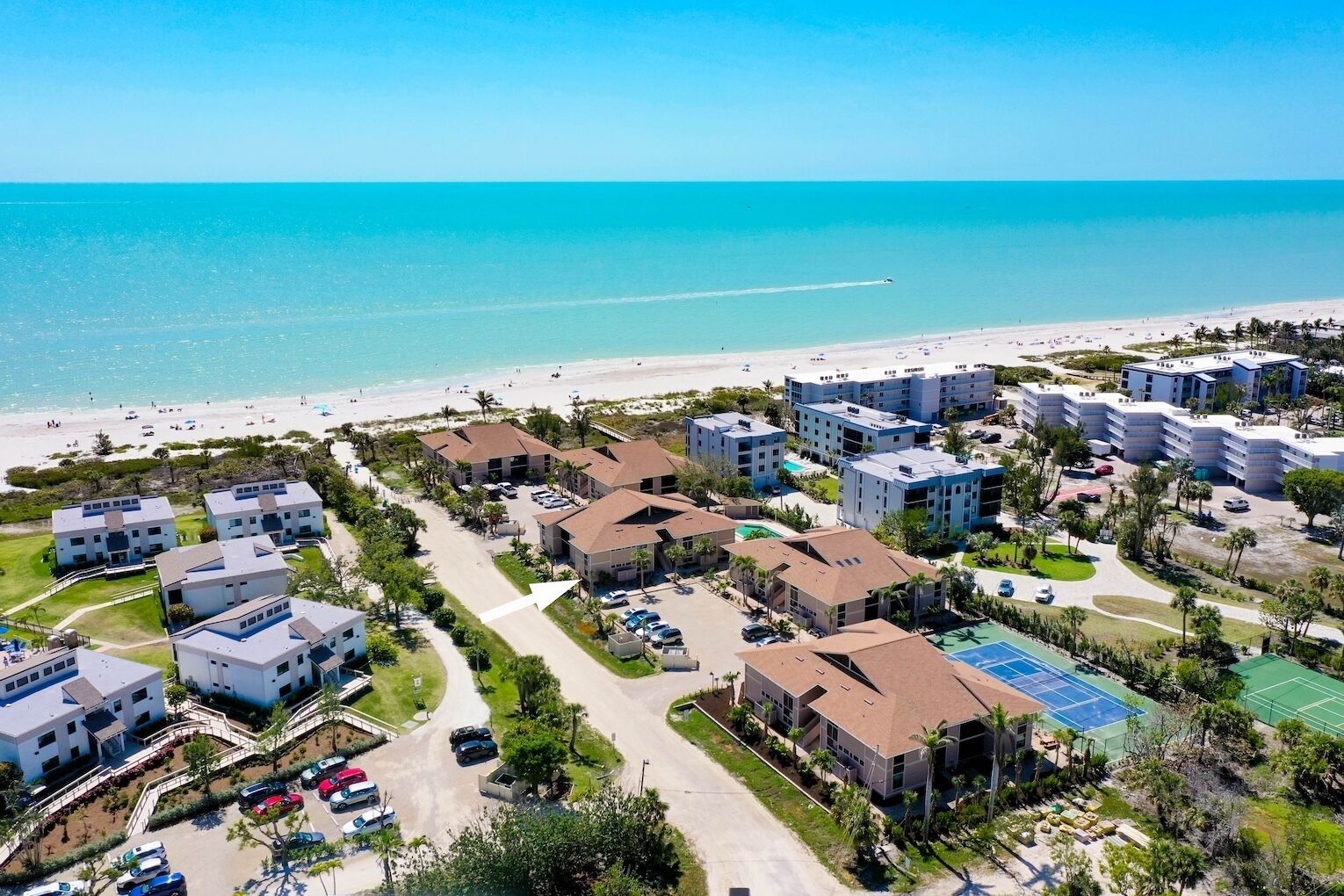 Un hotel costero con varias edificaciones, una playa y una vista despejada del océano.
