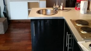 Une cuisine moderne dotée d’un évier en acier inoxydable, de meubles de rangement noirs et d’une cuisinière intégrée.