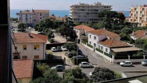 Un quartier résidentiel offrant une vue sur la mer, avec des immeubles à plusieurs étages, des voitures garées et un ciel dégagé.