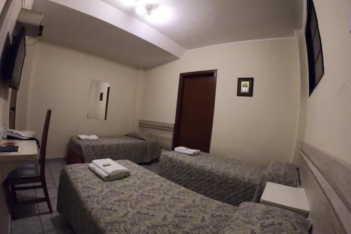 Habitación de hotel con dos camas, un escritorio, una silla, un televisor y una puerta.