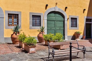 A courtyard with a bench, potted plants, and a green door. - Fienile (Montopoli in Val d'Arno)