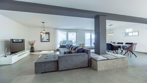 A spacious living area with a large sectional sofa, a dining table with chairs, and a flat-screen TV. - Villa Ancora - holiday house near the sea with a pool for up to ten guests by MyWaycation (Seget Donji)