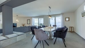 A modern dining area with a white table, black chairs, and a grey sofa.