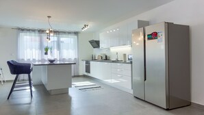 A modern kitchen with a central island, stainless steel appliances, and a dining area with a chair. - Villa Ancora - holiday house near the sea with a pool for up to ten guests by MyWaycation (Seget Donji)