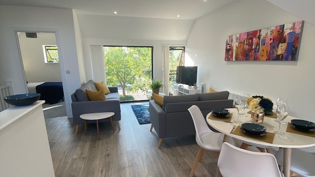 Uma sala de estar moderna com área de jantar, janelas amplas e um quadro na parede.