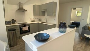 Cozinha moderna com ilha central, armários cinza e exaustor de aço inoxidável.