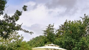 Een terras met rieten meubilair en een grote parasol.