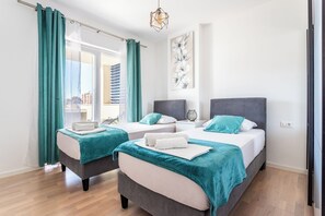 A hotel room with two beds, teal curtains, a city view, and a modern light fixture. - Luxury Modern Penthouse w Jacuzzi & Huge Terrace (Split)