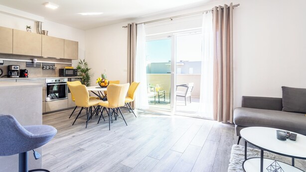 A modern kitchen with a dining area, a sofa, and a view through a sliding door to an outdoor space. - Luxury Modern Penthouse w Jacuzzi & Huge Terrace (Split)
