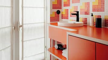 A bathroom with a tiled wall, a round mirror, a sink, and a cabinet.