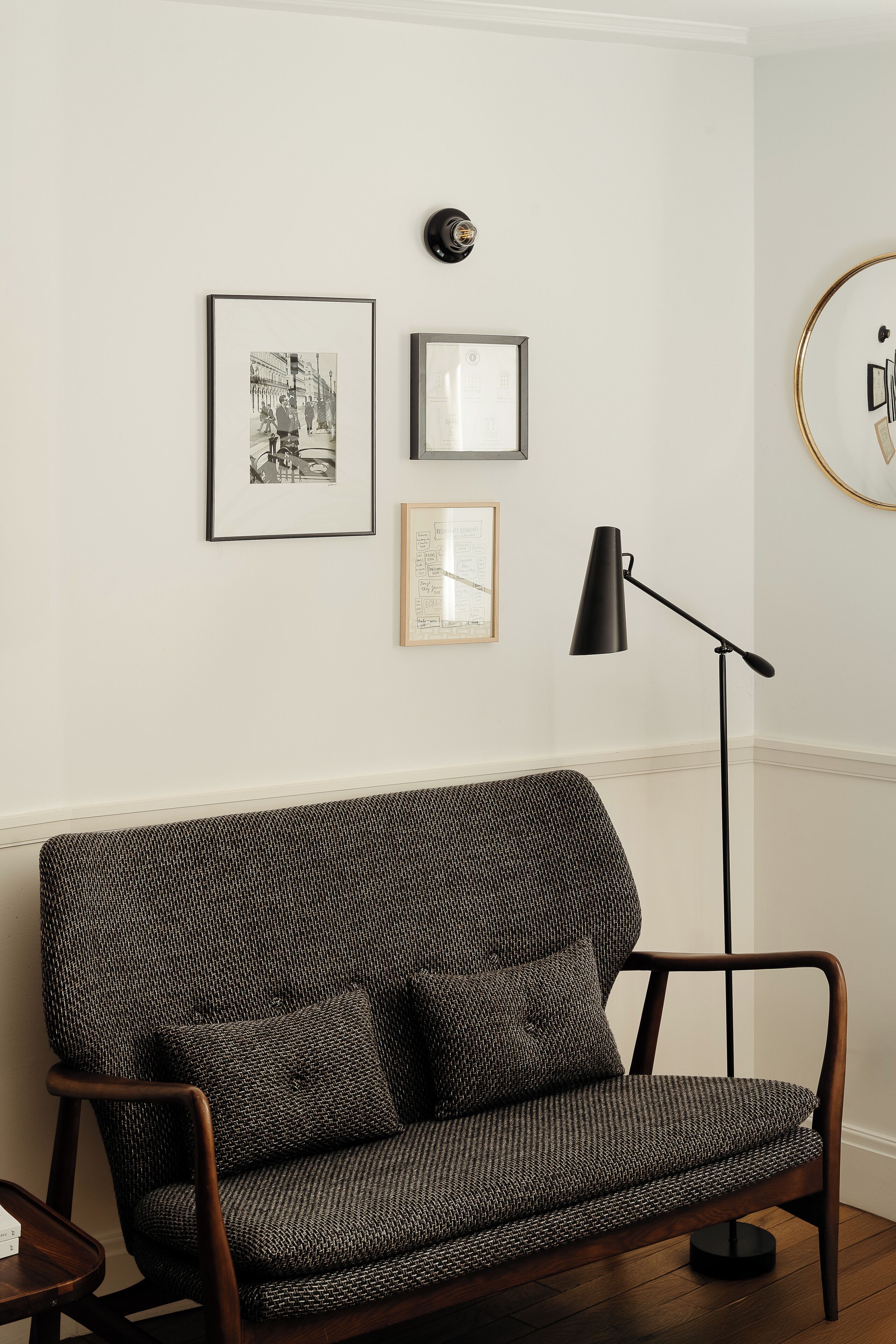 Ein modernes Wohnzimmer mit einem gemusterten Sofa, einer Stehlampe und gerahmten Bildern an der Wand.