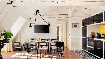 A dining area with a high ceiling, exposed beams, and a modern kitchen with black cabinets.