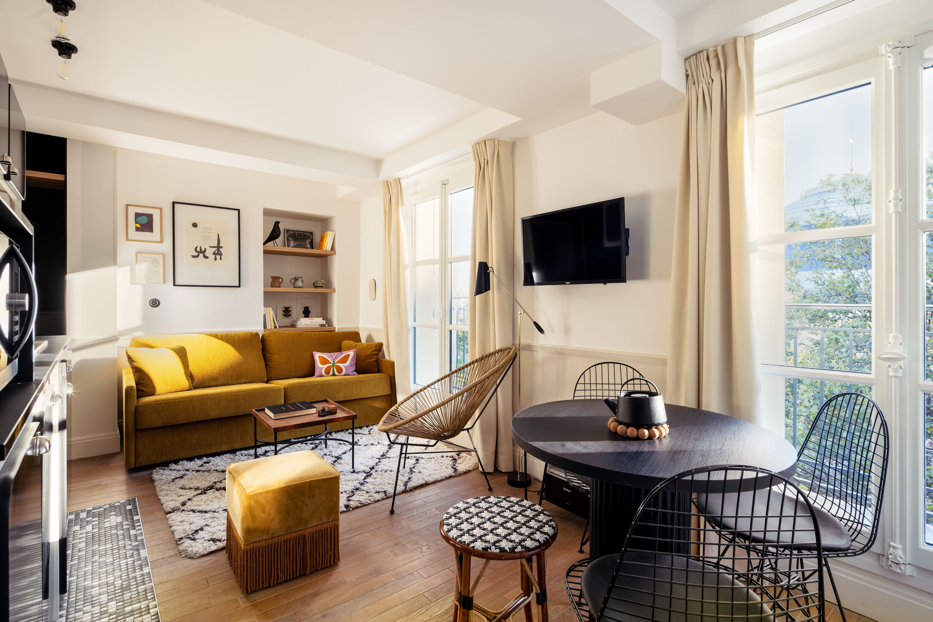 Ein modernes Wohnzimmer mit Sofa, Esstisch, Stühlen, Fernseher und Blick ins Freie.