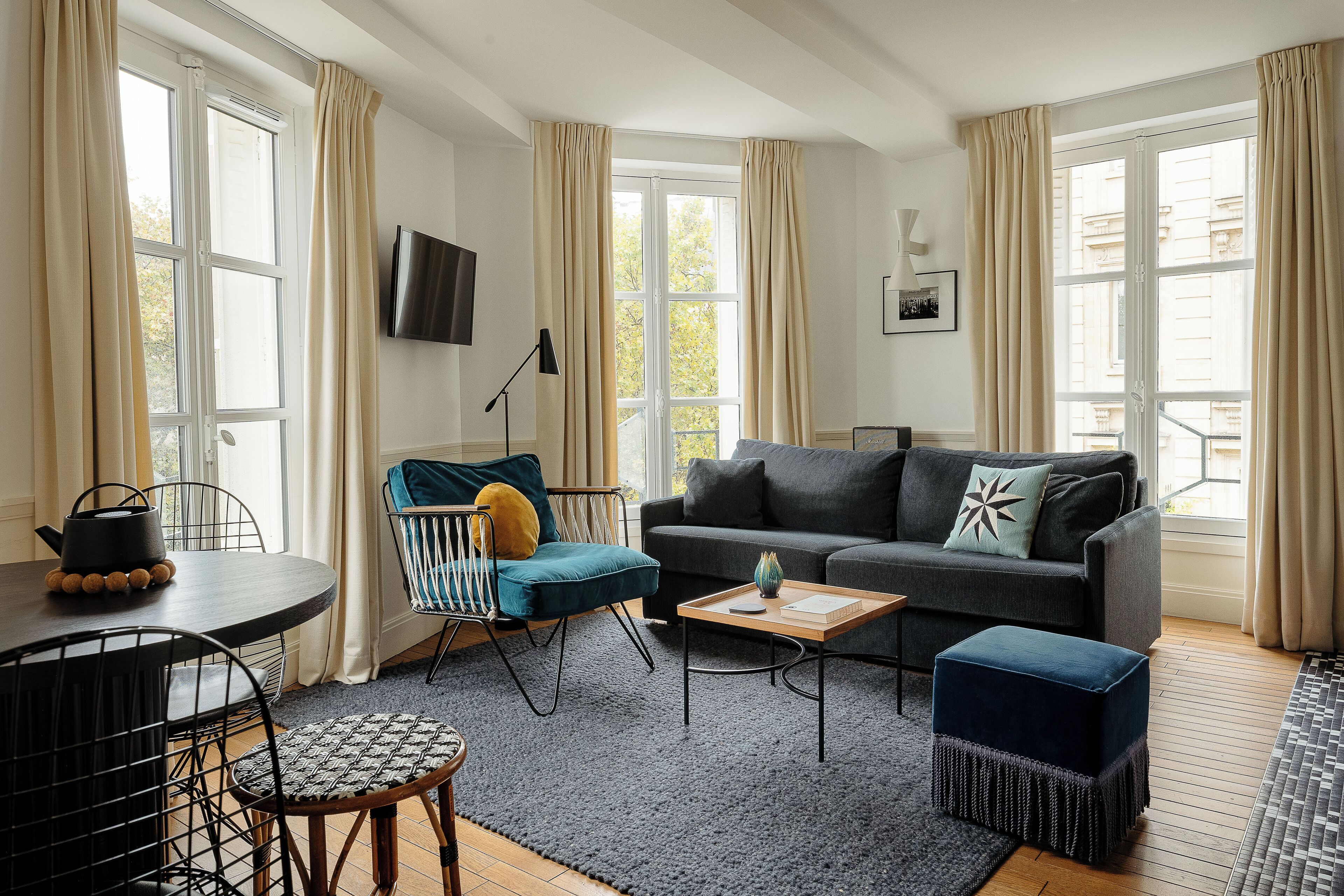 A modern living room with a sofa, armchair, coffee table, and dining area.