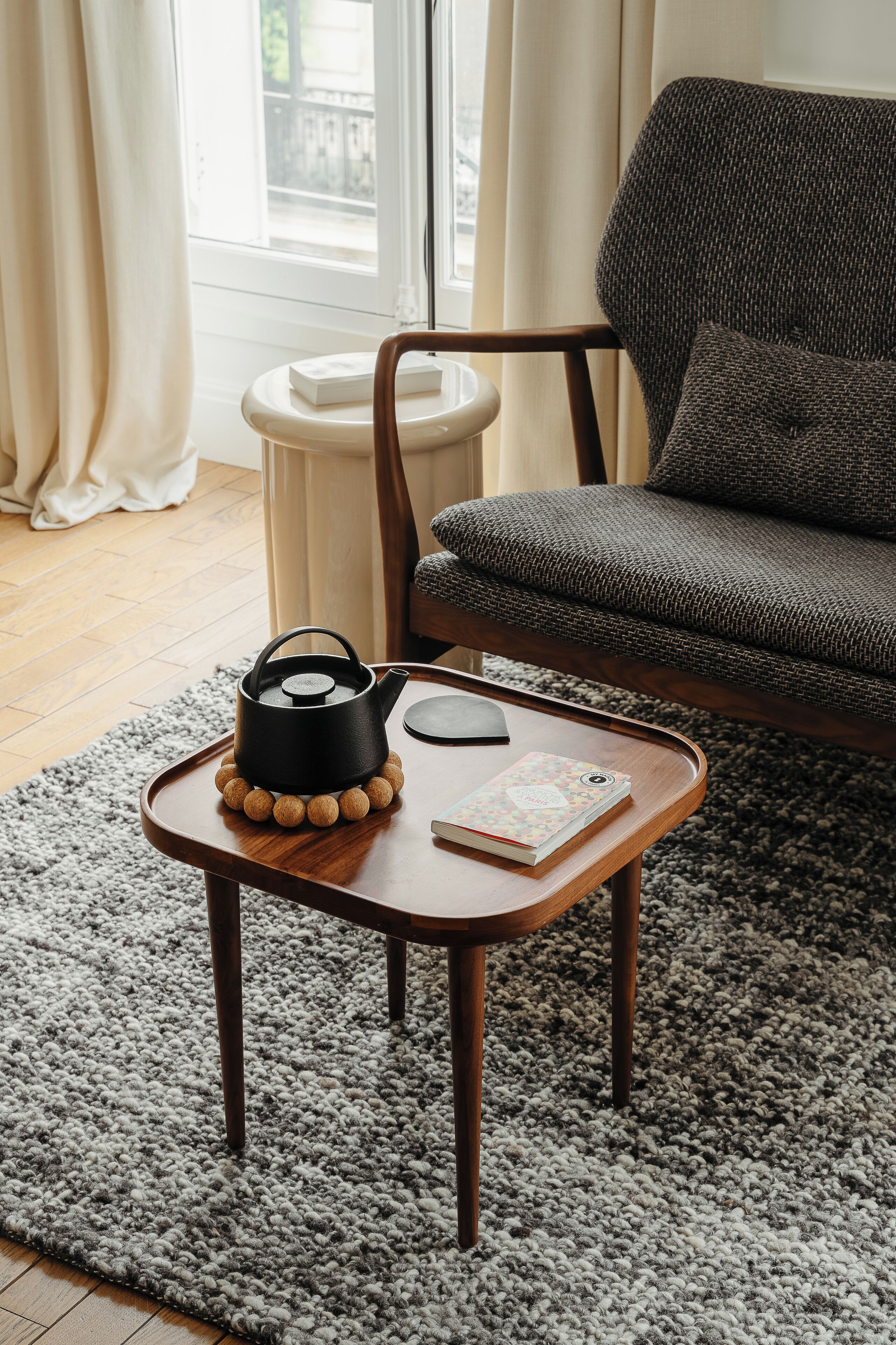Un salon chaleureux avec une table basse en bois, une bouilloire noire et un livre.