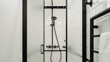 Una ducha moderna con puerta de cristal, marco negro y pared de azulejos blancos.