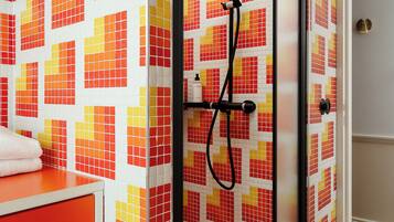 A shower enclosure with a tiled wall featuring a red and yellow pattern.