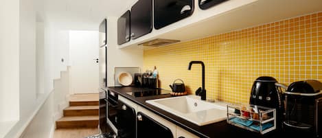 Una cocina moderna con gabinetes negros, un lavamanos blanco y un salpicadero amarillo de azulejos.
