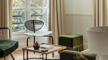 Una habitación con ventana, una silla, una mesa y una lámpara.
