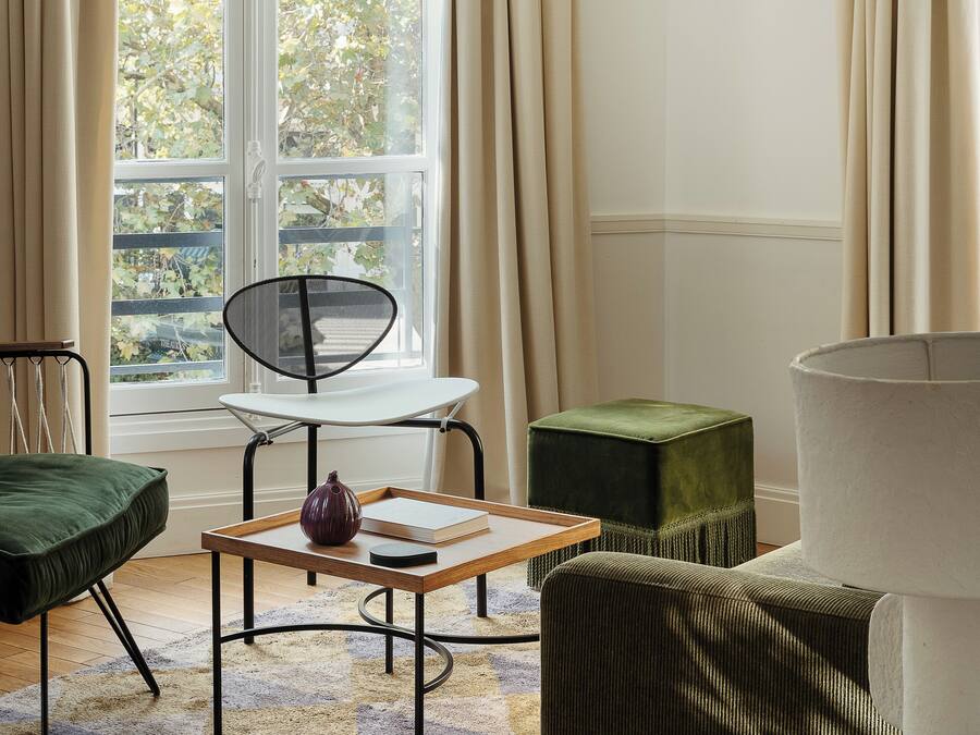 Una habitación con ventana, una silla, una mesa y una lámpara.