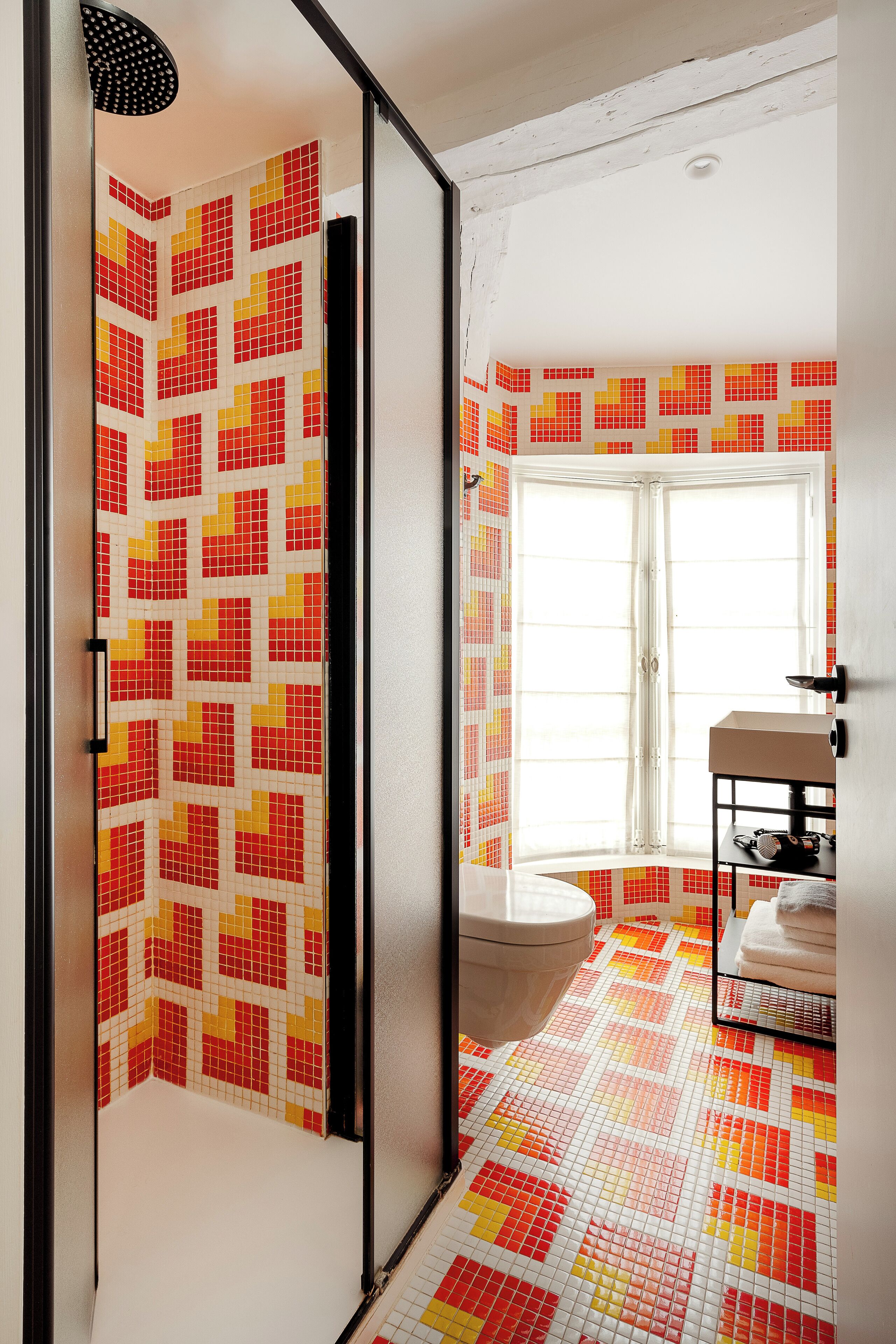 Een badkamer met betegelde vloer, toilet, wastafel en raam.
