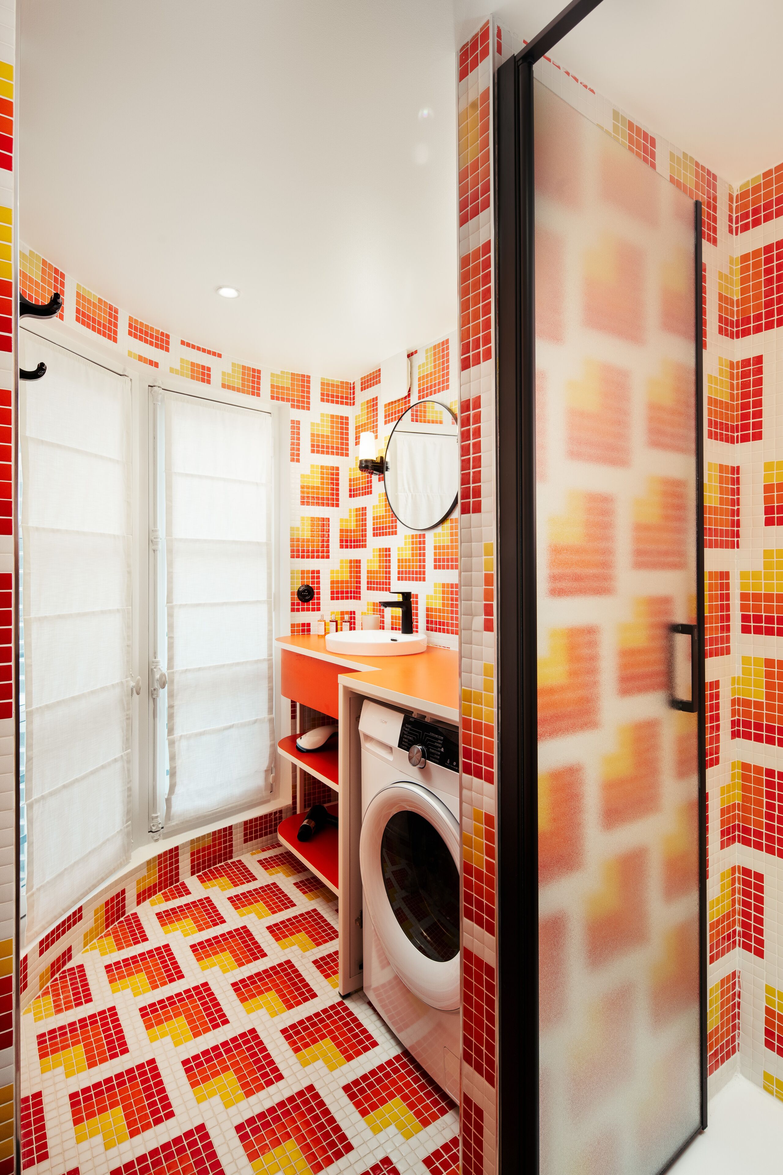 Een kleine badkamer met een wasmachine, een wastafel en een spiegel.