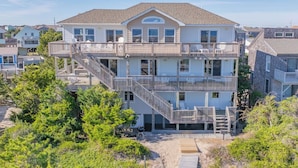 A multi-story beachfront property with a central staircase, balconies, and a covered outdoor area. - Oceanfront Dog Friendly Home in Avon w/ Elevator, Hot Tub, Game Room, Wet Bar (Avon)