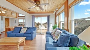 Un salón espacioso con techo de madera, ventanas amplias y vistas al vecindario.