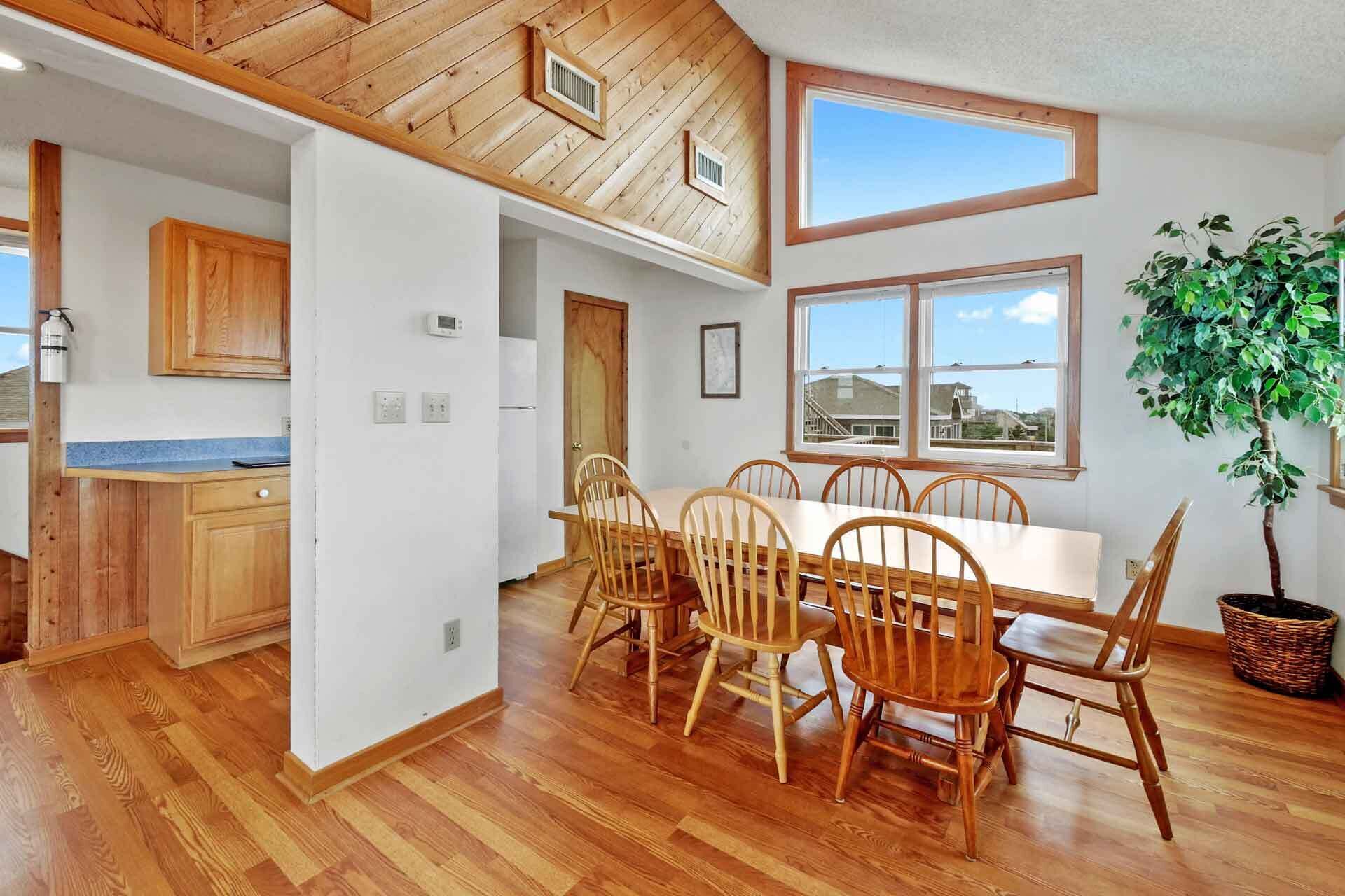 Une cuisine spacieuse, dotée de meubles de rangement en bois et d’un coin repas avec une grande table et des chaises.