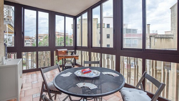 A balcony with a round table, chairs, and a grill. - Cozy Syracuse House (Siracusa)