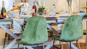 A dining area with a modern chandelier, green upholstered chairs, and a table set with various items including bottles and glasses. - A Seaside Sanctuary in the Heart of Viareggio (Viareggio)