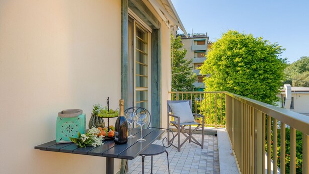 A balcony with a table set for two, a chair, and a potted plant. - A Seaside Sanctuary in the Heart of Viareggio (Viareggio)