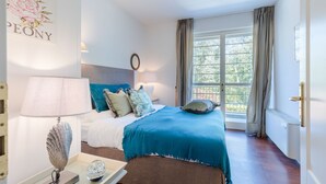 A bedroom with a bed, a bedside table with a lamp, a decorative wall piece, and a window with curtains. - A Seaside Sanctuary in the Heart of Viareggio (Viareggio)