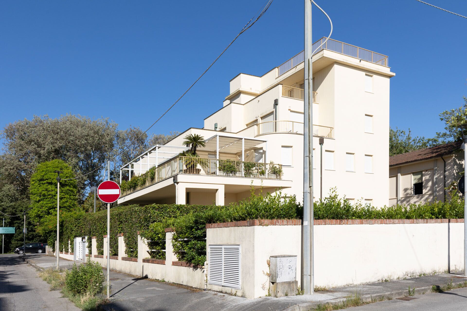 A multi-story residential building with balconies, a no-entry sign, and a street sign.