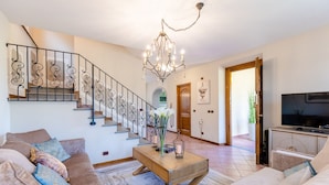 A living room with a staircase, a chandelier, a sofa set, a coffee table, and a television. - Nonna Bianca, a Genuine Farmhouse in Sant'Alessio, Lucca (Lucca)