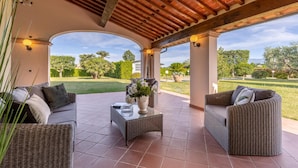 A covered patio with wicker furniture, a glass coffee table, and a view of a landscaped garden. - Nonna Bianca, a Genuine Farmhouse in Sant'Alessio, Lucca (Lucca)