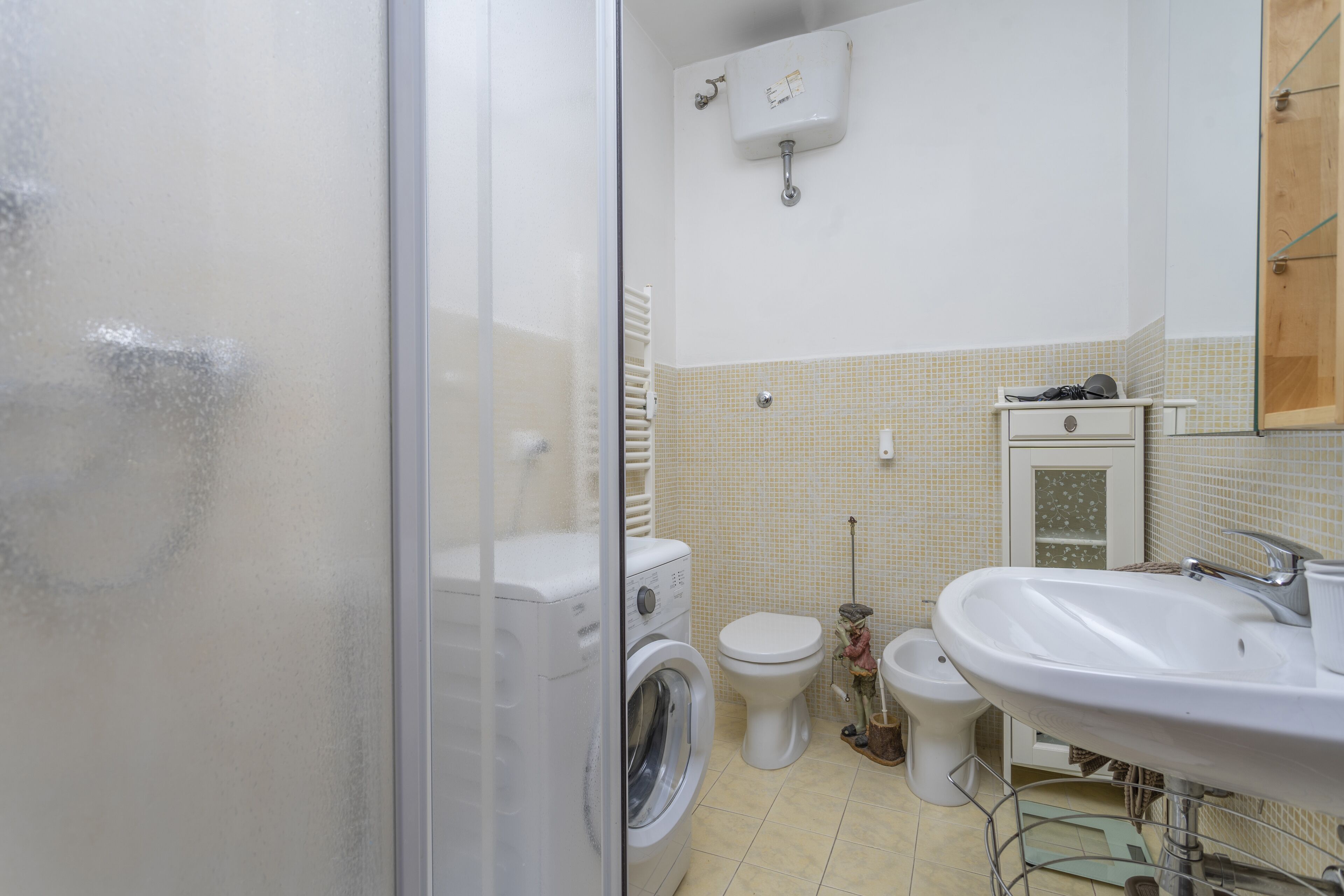 Une salle de bain équipée d’un lave-linge, de toilettes, d’un bidet et d’un lavabo.