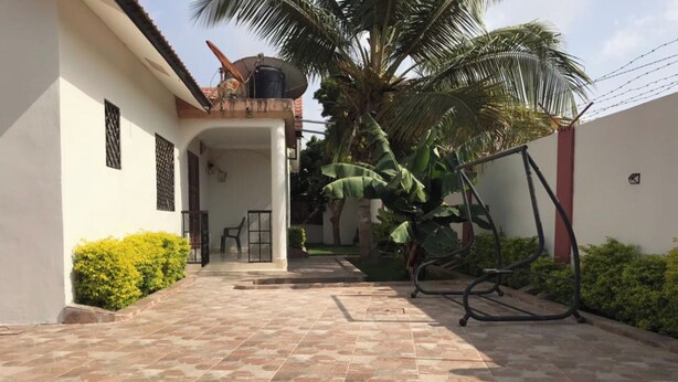 Un patio empedrado con una palmera y un conjunto de columpios.