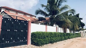 Propiedad amurallada con muro de ladrillo, una palmera y una antena parabólica.
