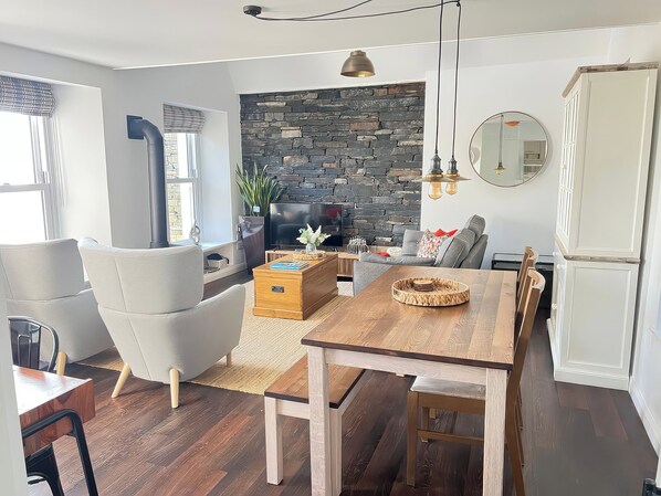 A modern living room with a stone wall, a wooden dining table, and a comfortable seating area.