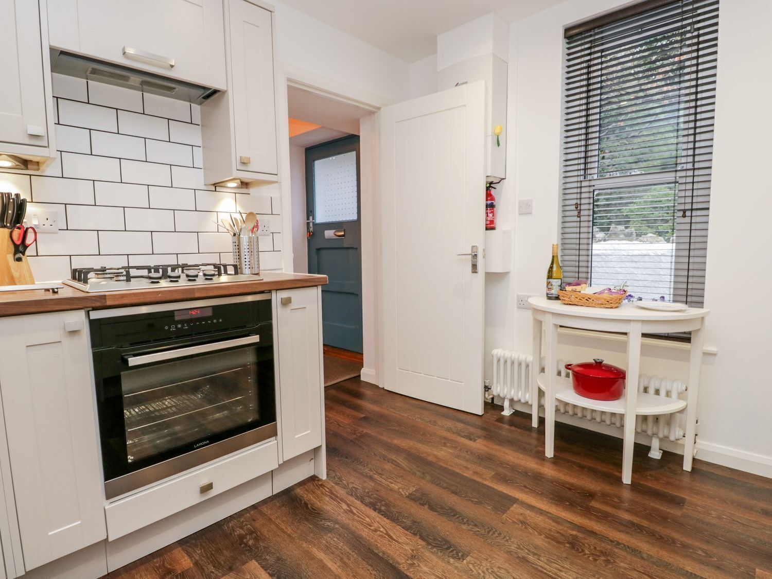 Eine kleine Küche mit weißen Schränken, einem eingebauten Backofen und einer Holz Arbeitsplatte.