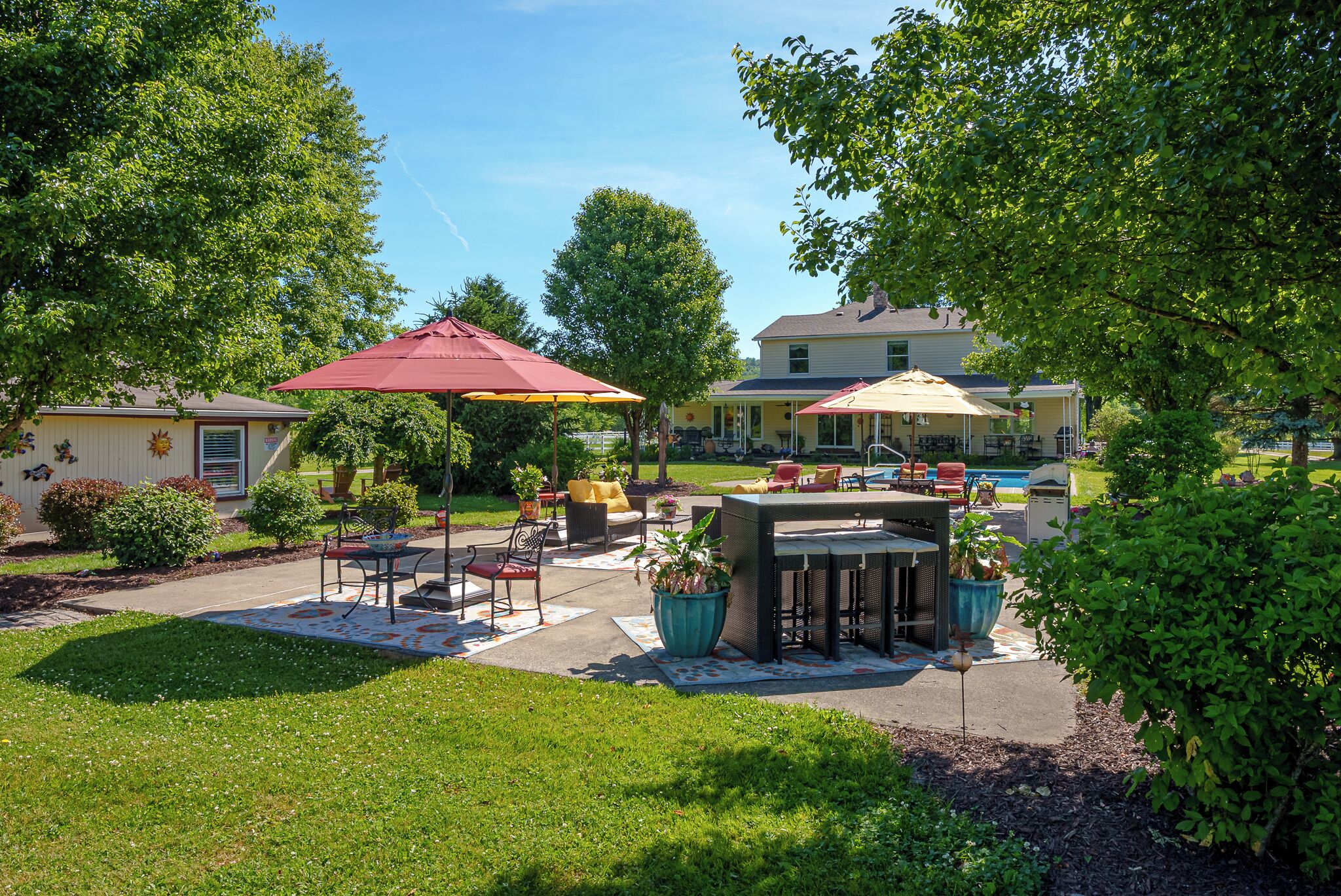 A patio area with outdoor furniture, a barbecue grill, and a swimming pool in the background.