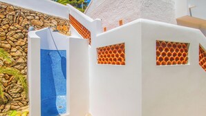 Un edificio blanco con piscina de azulejos azules y una pared de piedra.