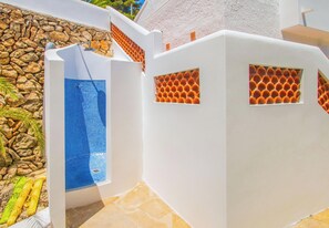 A white building with a blue tiled pool and a stone wall.